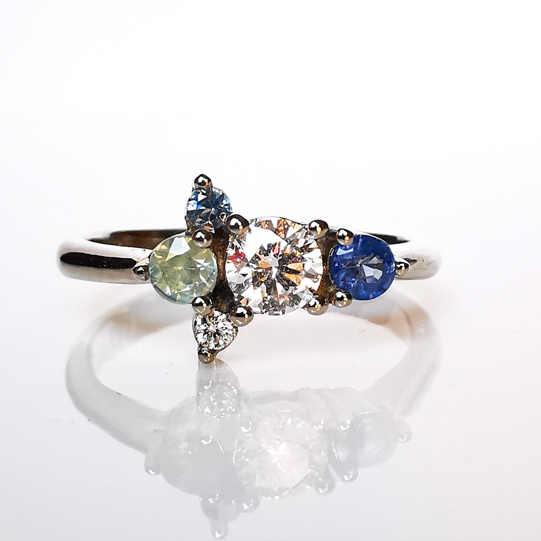 Alt: Anillo de compromiso Fiesta asimétrico en oro blanco paladio con diamante y zafiros fancy