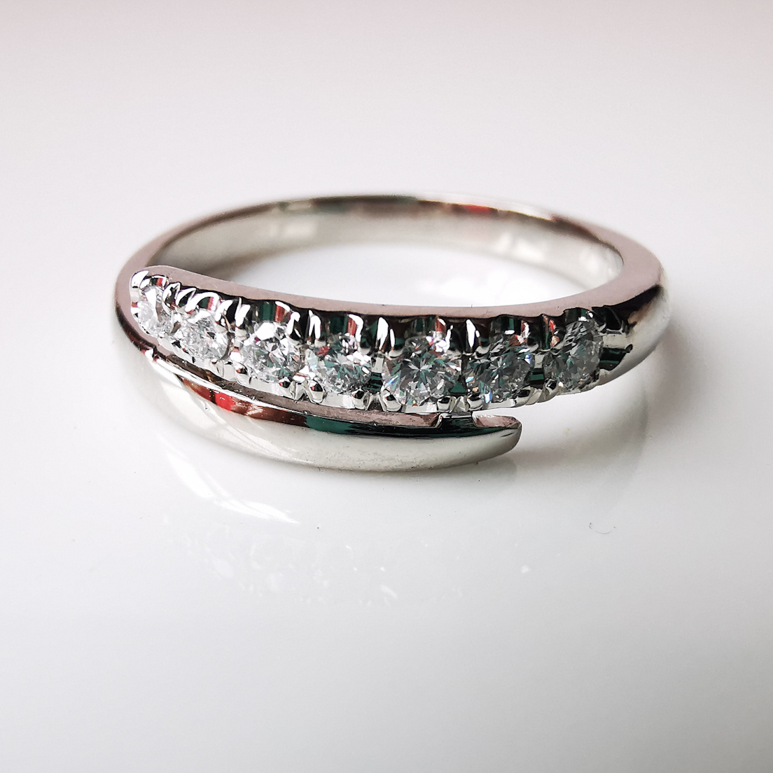 Alt: Anillo medio cintillo de platino con diamantes en degradé de tamaño.